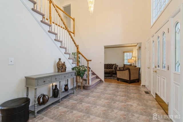 entryway featuring stairway, visible vents, and a towering ceiling