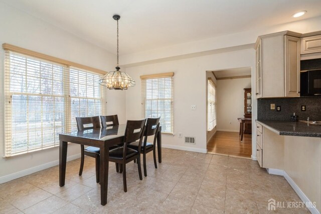 dining area featuring light tile patterned floors, visible vents, an inviting chandelier, and baseboards