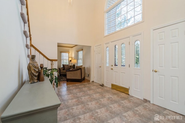 foyer entrance with stairway and a towering ceiling