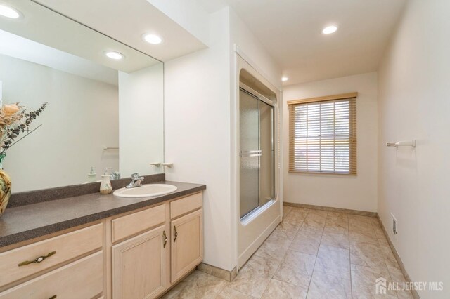 bathroom with vanity, recessed lighting, baseboards, and enclosed tub / shower combo