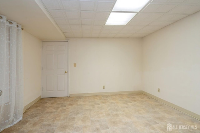 empty room featuring a drop ceiling and baseboards