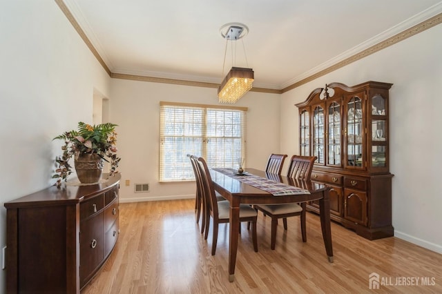 dining area with crown molding, baseboards, visible vents, and light wood finished floors