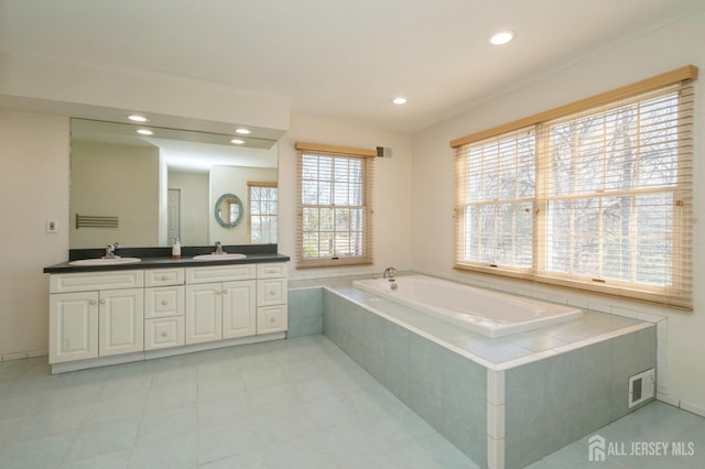 bathroom featuring double vanity, a bath, visible vents, and a sink