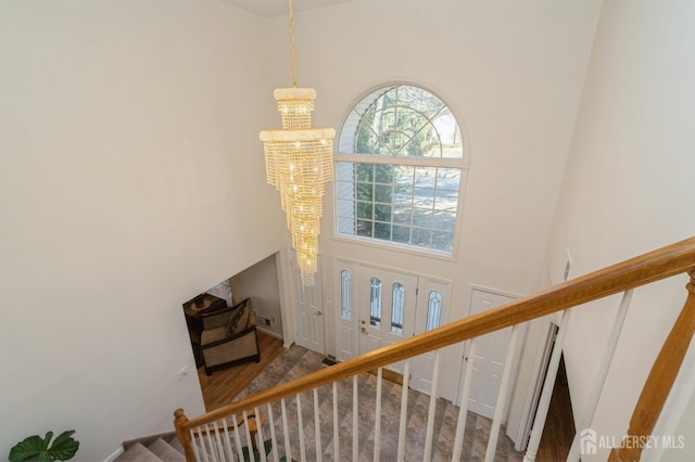 staircase with a chandelier, a towering ceiling, and wood finished floors