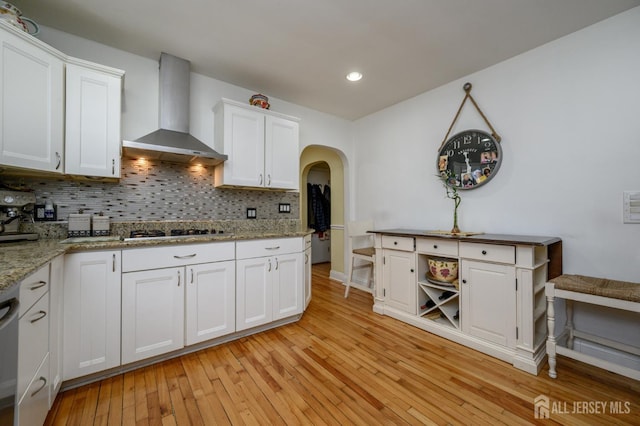 1156 Kline Pl, Rahway, NJ 07065 - kitchen featuring wall chimney exhaust hood, decorative backsplash, white cabinets, light wood-style floors, and arched walkways