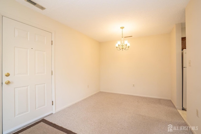 empty room featuring light carpet, a chandelier, and baseboards