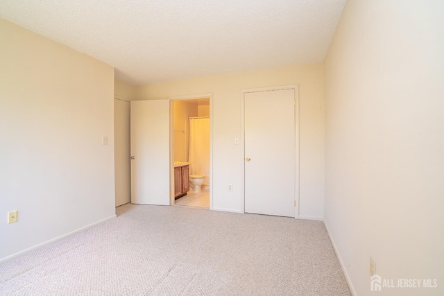 unfurnished bedroom featuring light carpet, baseboards, and connected bathroom