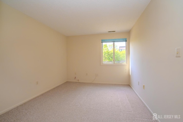 unfurnished room with light carpet and baseboards