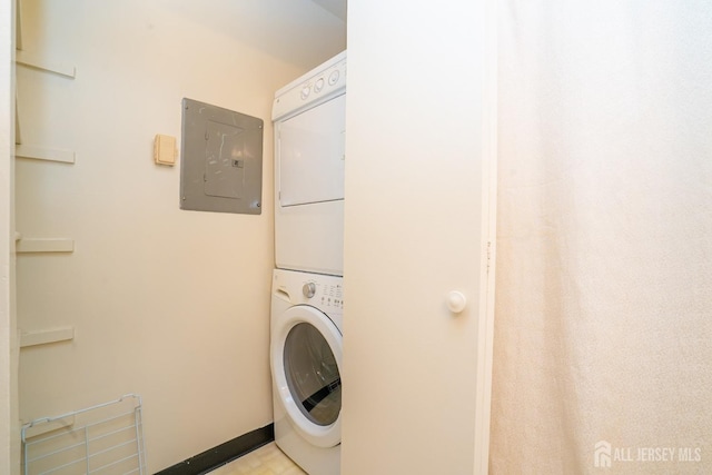 washroom with stacked washing machine and dryer and electric panel