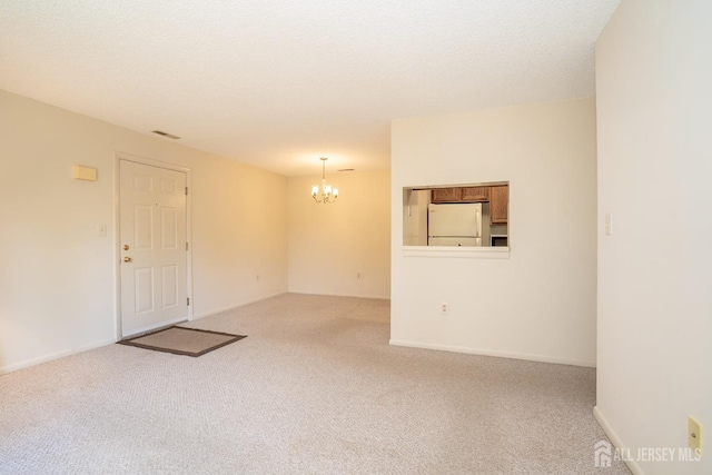 carpeted spare room featuring a chandelier and baseboards