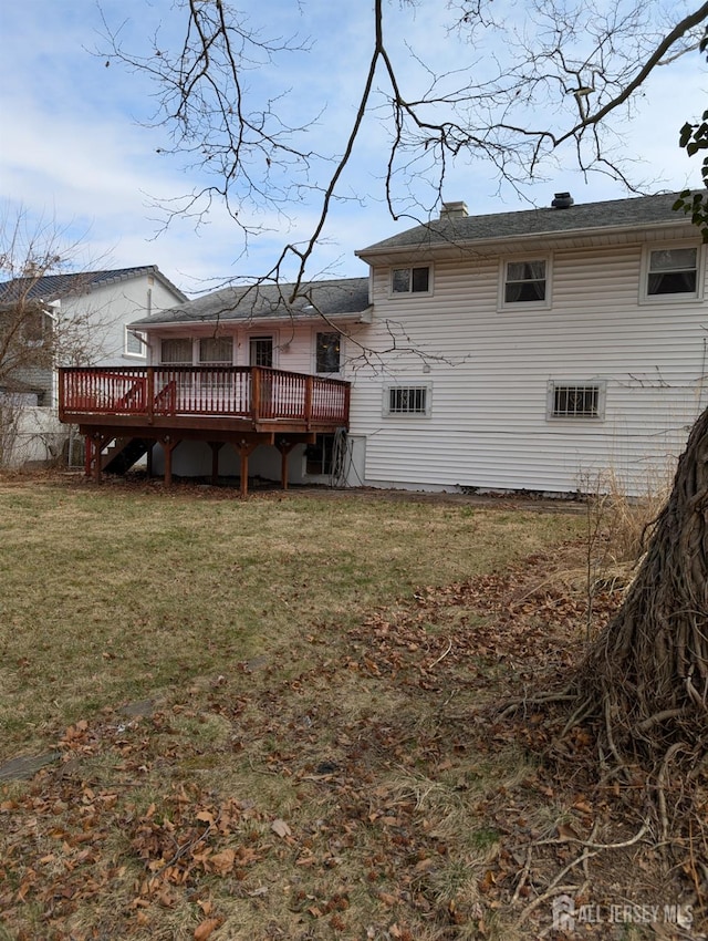 rear view of property featuring a lawn and a wooden deck