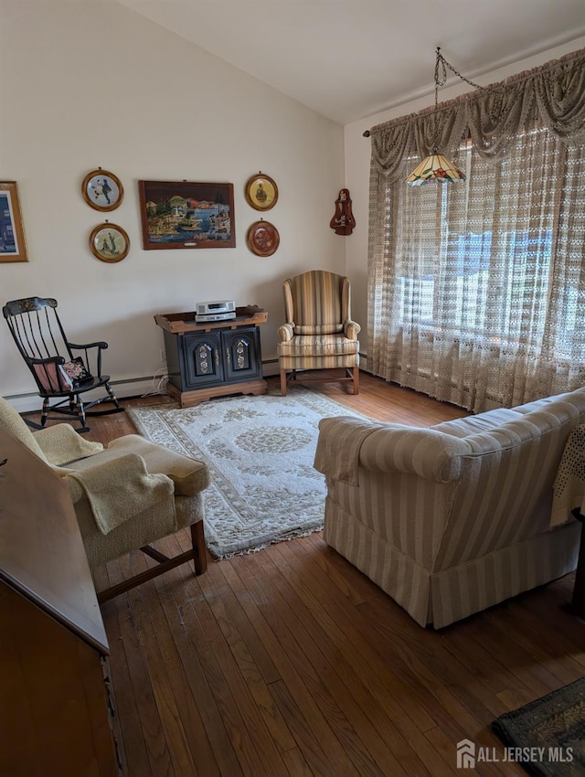 living area featuring a baseboard heating unit, lofted ceiling, and wood-type flooring