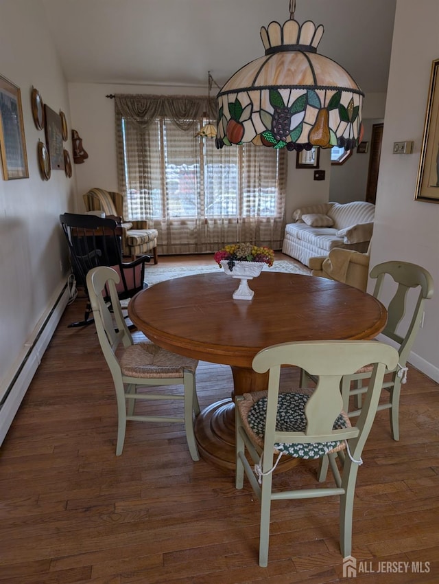 dining space with a baseboard heating unit, wood finished floors, and baseboards