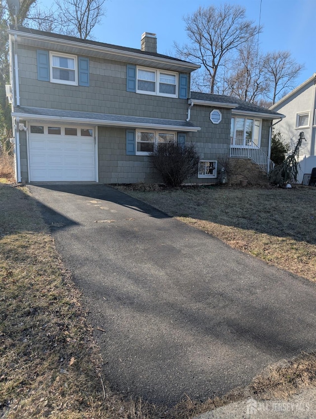 view of front of property featuring a garage, driveway, and a chimney