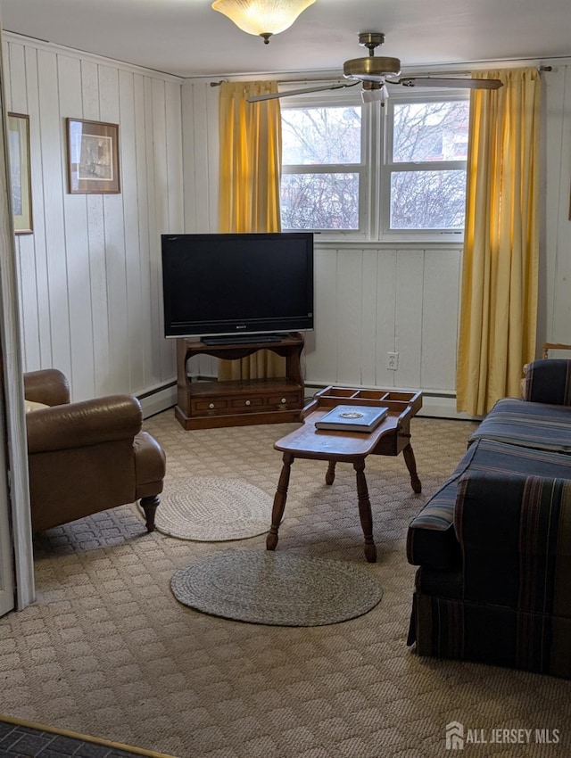 living area with a baseboard heating unit, a ceiling fan, and carpet floors