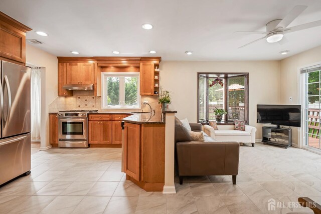 44 Frost Ave, East Brunswick, NJ 08816 - kitchen featuring appliances with stainless steel finishes, under cabinet range hood, brown cabinets, open floor plan, and tasteful backsplash