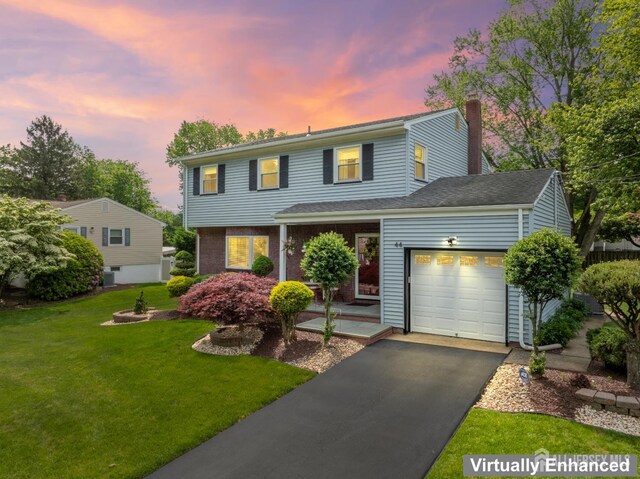 44 Frost Ave, East Brunswick, NJ 08816 - view of front facade featuring a garage, a chimney, driveway, and a lawn