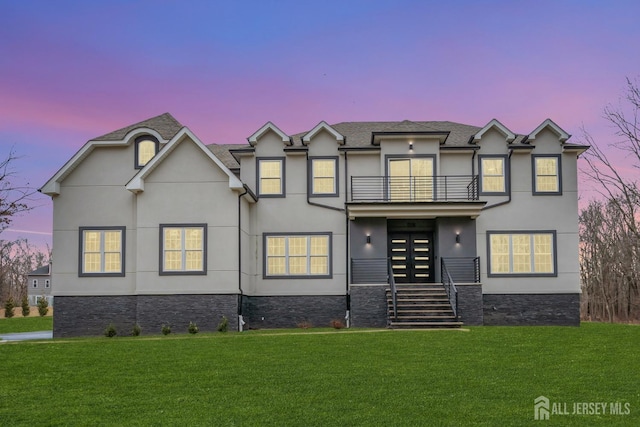 view of front of home with a lawn, french doors, and a balcony