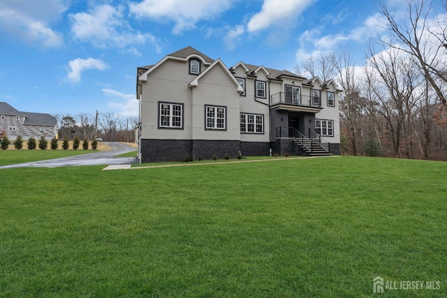 view of front of home with a balcony and a front yard