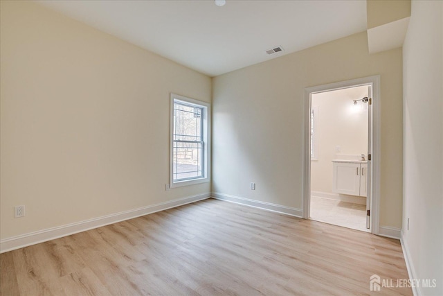 spare room featuring baseboards, visible vents, and light wood-style floors