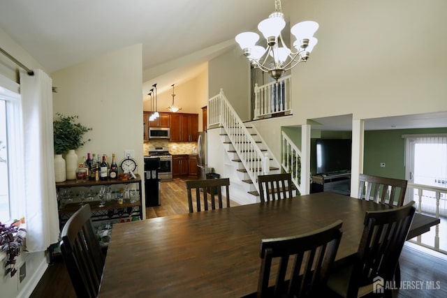 dining space with a notable chandelier, wood-type flooring, and high vaulted ceiling