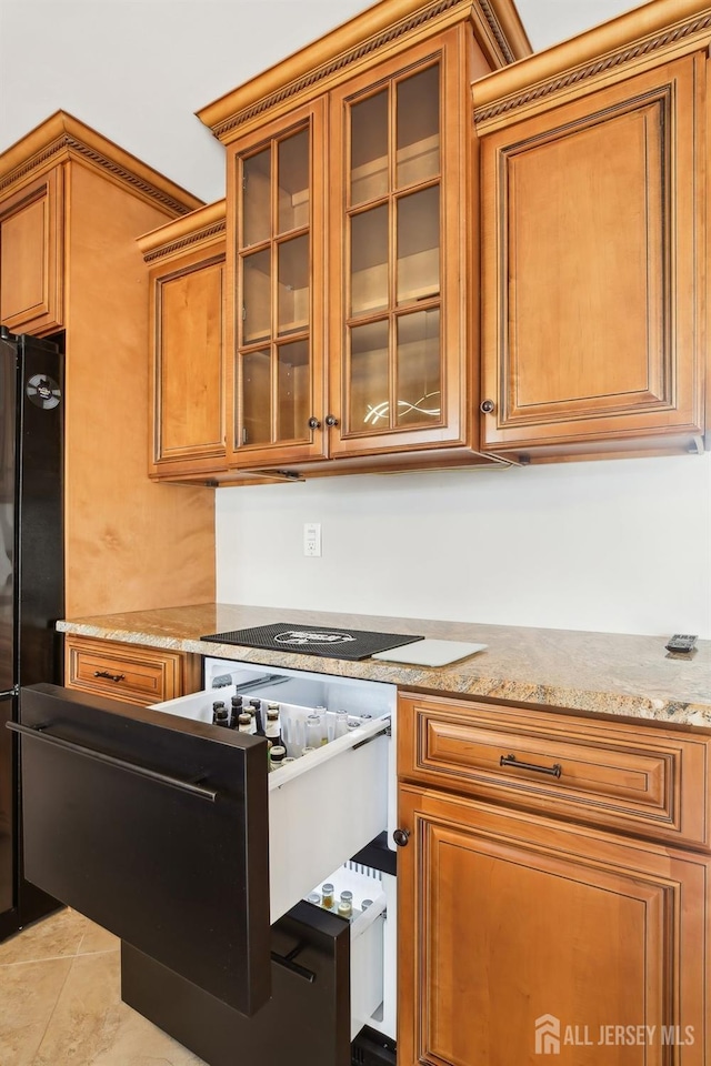 415 Lorillard Ave, Union Beach, NJ 07735 - kitchen featuring glass insert cabinets, light stone counters, freestanding refrigerator, and brown cabinets