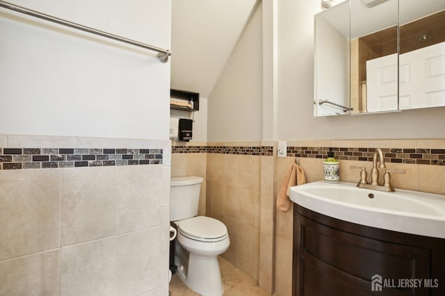 415 Lorillard Ave, Union Beach, NJ 07735 - bathroom featuring wainscoting, vanity, toilet, tile walls, and vaulted ceiling