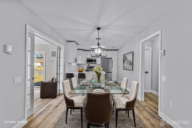 dining space featuring baseboards, light wood finished floors, and an inviting chandelier