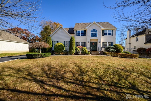 colonial-style house featuring a front lawn