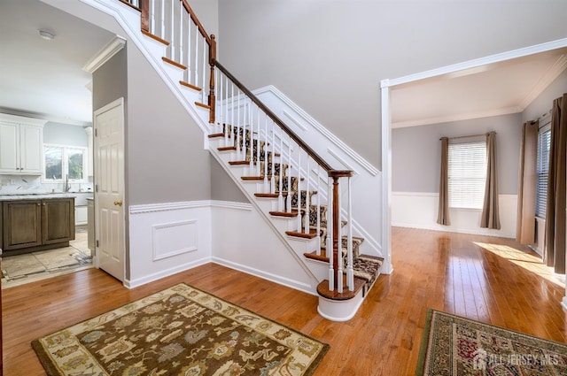 stairway featuring ornamental molding, wood-type flooring, and plenty of natural light