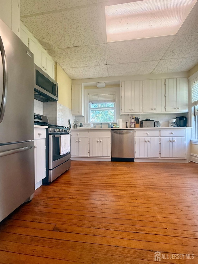 451 E Main St, Somerville, NJ 08876 - kitchen featuring appliances with stainless steel finishes, a drop ceiling, white cabinetry, light wood-style flooring, and backsplash