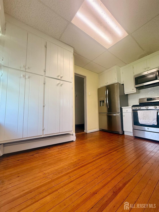 451 E Main St, Somerville, NJ 08876 - kitchen with stainless steel appliances, a paneled ceiling, wood-type flooring, white cabinetry, and tasteful backsplash