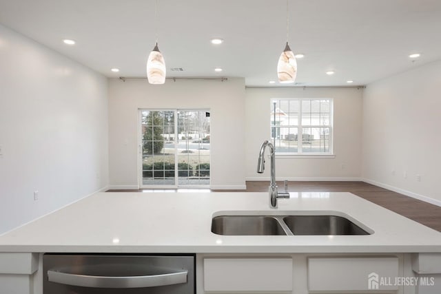 kitchen with hanging light fixtures, white cabinets, dishwasher, and a sink