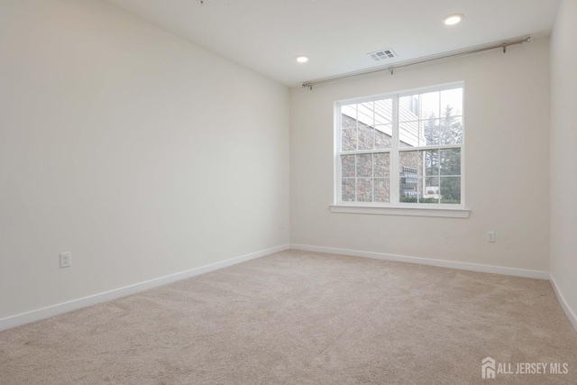 empty room featuring light carpet, baseboards, visible vents, and recessed lighting