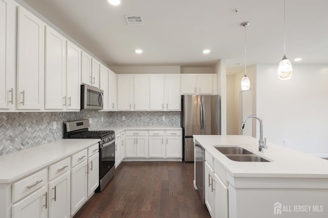 kitchen with stainless steel appliances, a sink, visible vents, white cabinetry, and decorative light fixtures