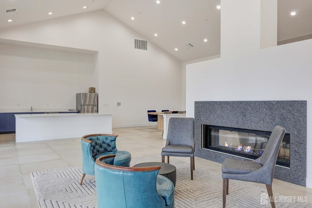 interior space featuring light tile patterned floors, a fireplace, visible vents, and high vaulted ceiling