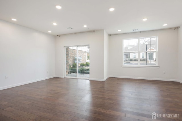 empty room with dark wood-type flooring and recessed lighting