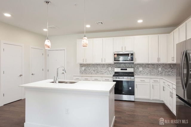 kitchen featuring stainless steel appliances, a sink, white cabinets, light countertops, and decorative light fixtures