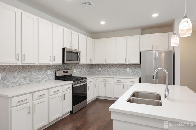 kitchen with visible vents, a sink, dark wood-type flooring, appliances with stainless steel finishes, and tasteful backsplash