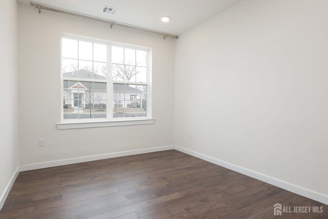 empty room with visible vents, dark wood finished floors, and baseboards