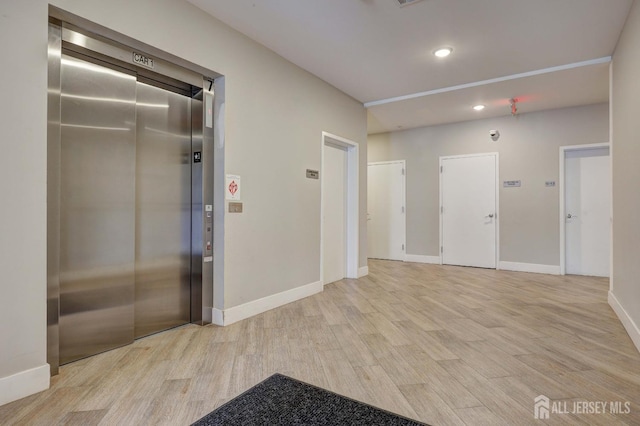 interior space featuring recessed lighting, elevator, baseboards, and light wood-type flooring