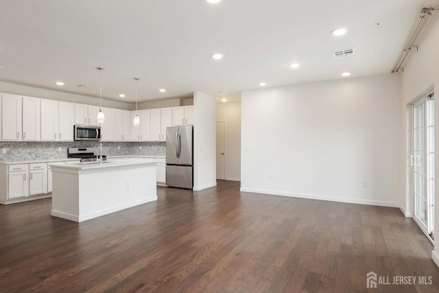 kitchen with a kitchen island with sink, stainless steel appliances, light countertops, and white cabinetry