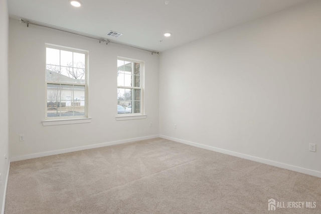 spare room featuring light carpet, recessed lighting, and baseboards