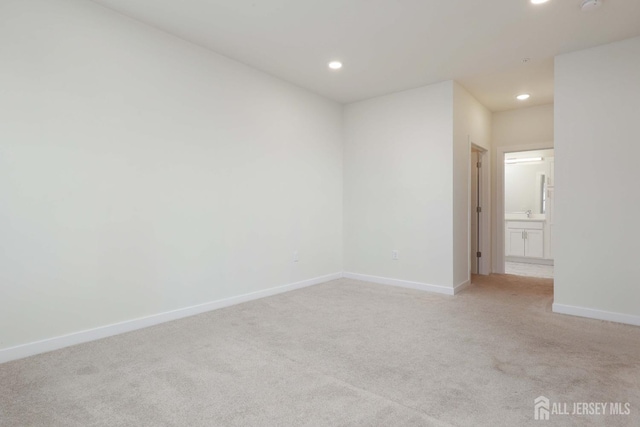 spare room featuring recessed lighting, light colored carpet, and baseboards