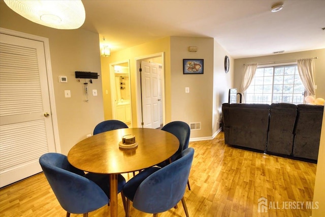 dining area featuring visible vents, baseboards, and light wood finished floors