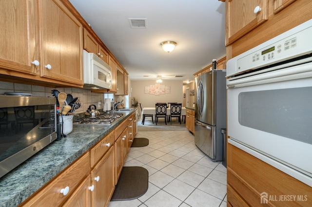 17 Duane St, Jamesburg, NJ 08831 - kitchen featuring appliances with stainless steel finishes, light tile patterned flooring, tasteful backsplash, dark countertops, and brown cabinets