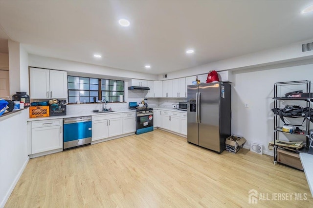 36 Henry St, Edison, NJ 08820 - kitchen featuring stainless steel appliances, light countertops, light wood finished floors, tasteful backsplash, and white cabinetry