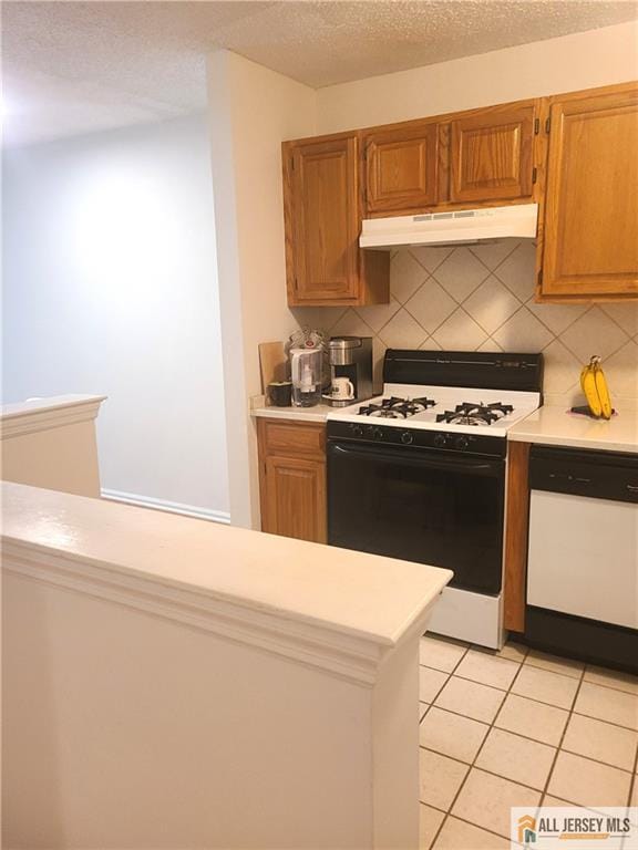 297 Prestwick Way Unit 297, Edison, NJ 08820 - kitchen with white gas stove, under cabinet range hood, light countertops, tasteful backsplash, and a textured ceiling