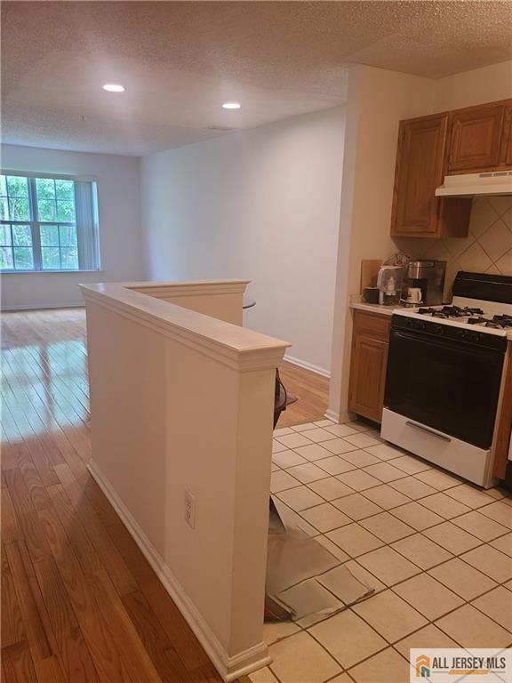297 Prestwick Way Unit 297, Edison, NJ 08820 - kitchen with white gas range oven, a textured ceiling, under cabinet range hood, recessed lighting, and decorative backsplash