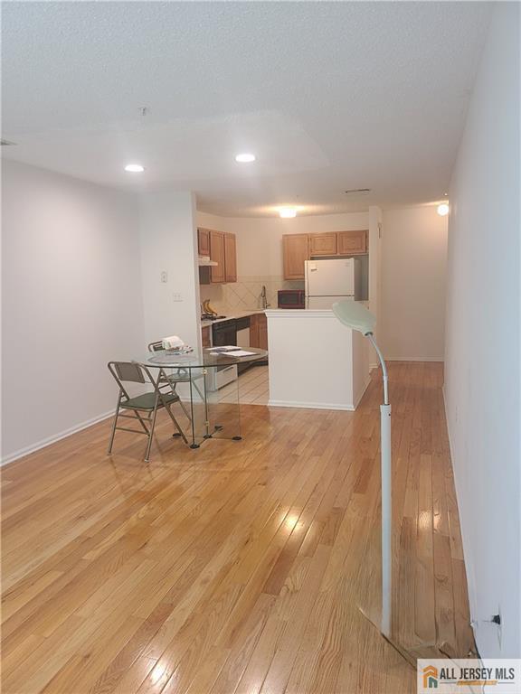 297 Prestwick Way Unit 297, Edison, NJ 08820 - kitchen featuring freestanding refrigerator, light wood-style floors, recessed lighting, brown cabinets, and stainless steel microwave